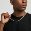 A person wearing a black shirt holding a silver Cuban link chain necklace.