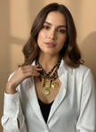 Woman wearing a white shirt and multiple necklaces with a neutral background