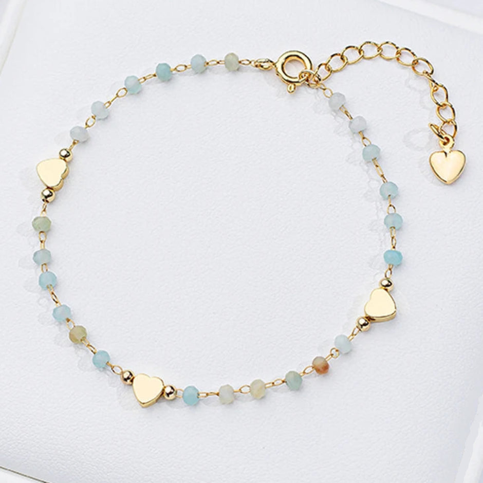 Delicate bracelet with heart-shaped beads on a white surface