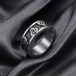 Silver ring with intricate design on a dark fabric background