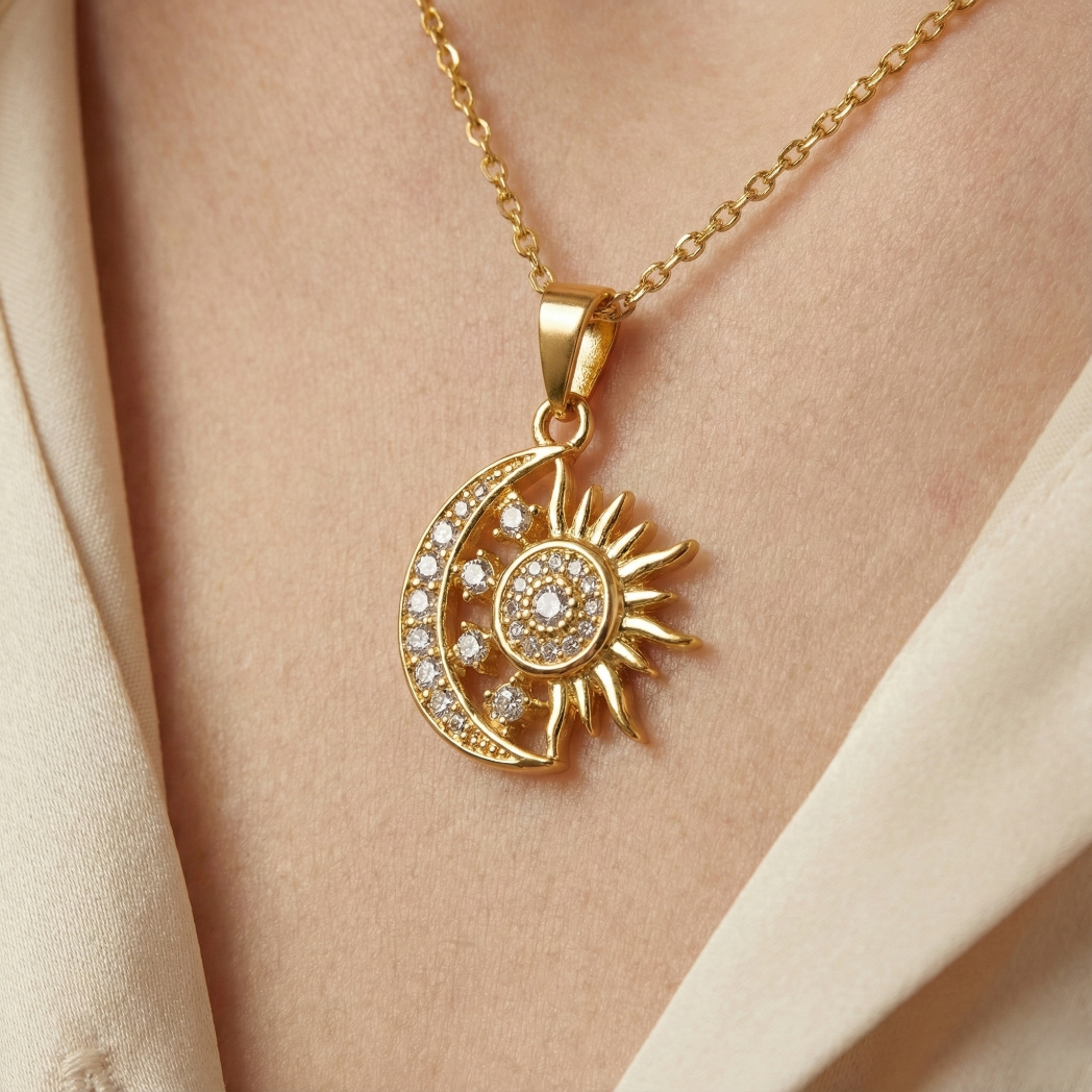 Gold necklace with sun and moon pendant on a person's neck against a beige background