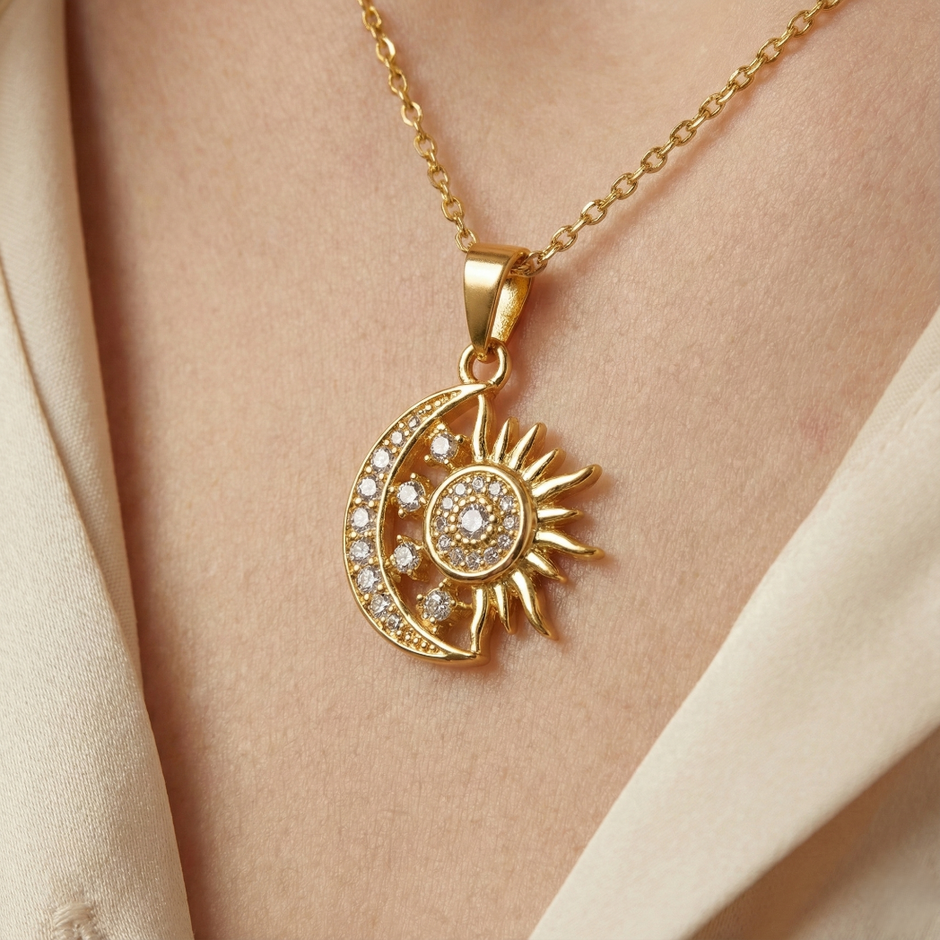 Gold necklace with sun and moon pendant on a person's neck against a beige background