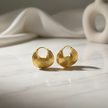Gold hoop earrings on a light surface with a blurred background