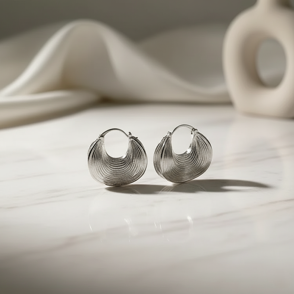 Silver hoop earrings on a light surface with a soft background