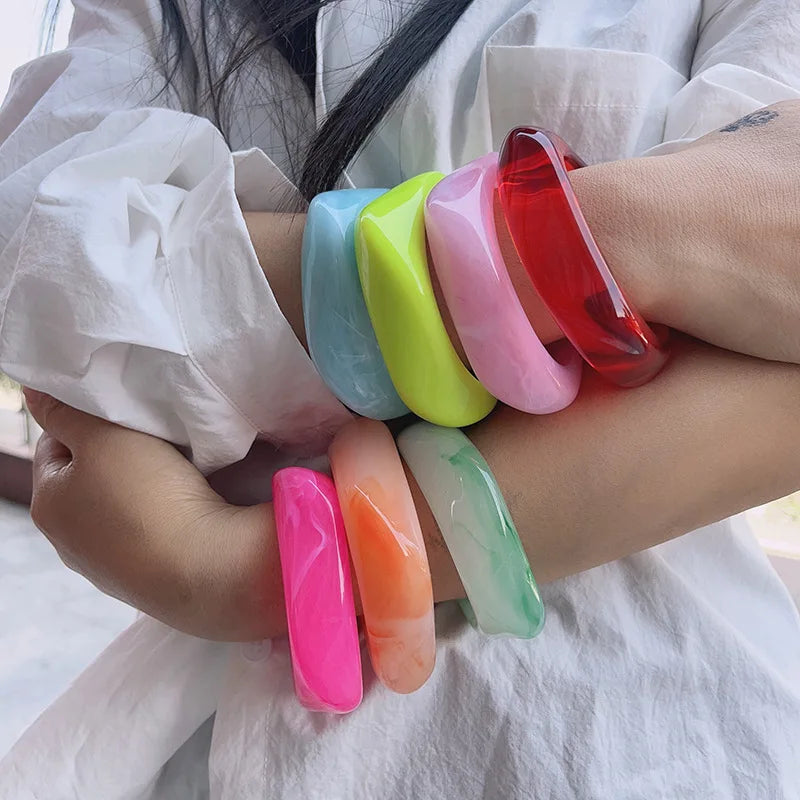 Colorful bangles on a person's wrist with a white shirt background