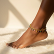 Anchored anklet with colorful beads on a foot against a neutral background