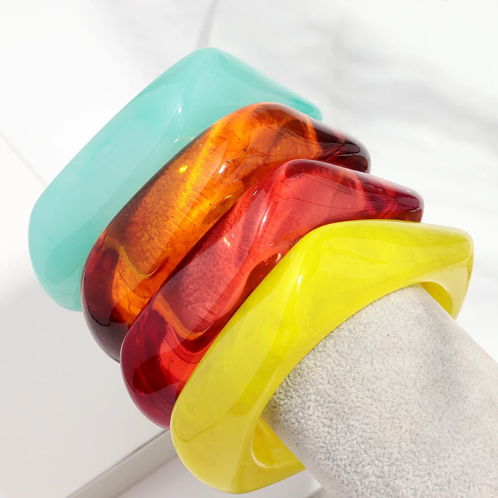 Stack of colorful resin bangles on a white surface