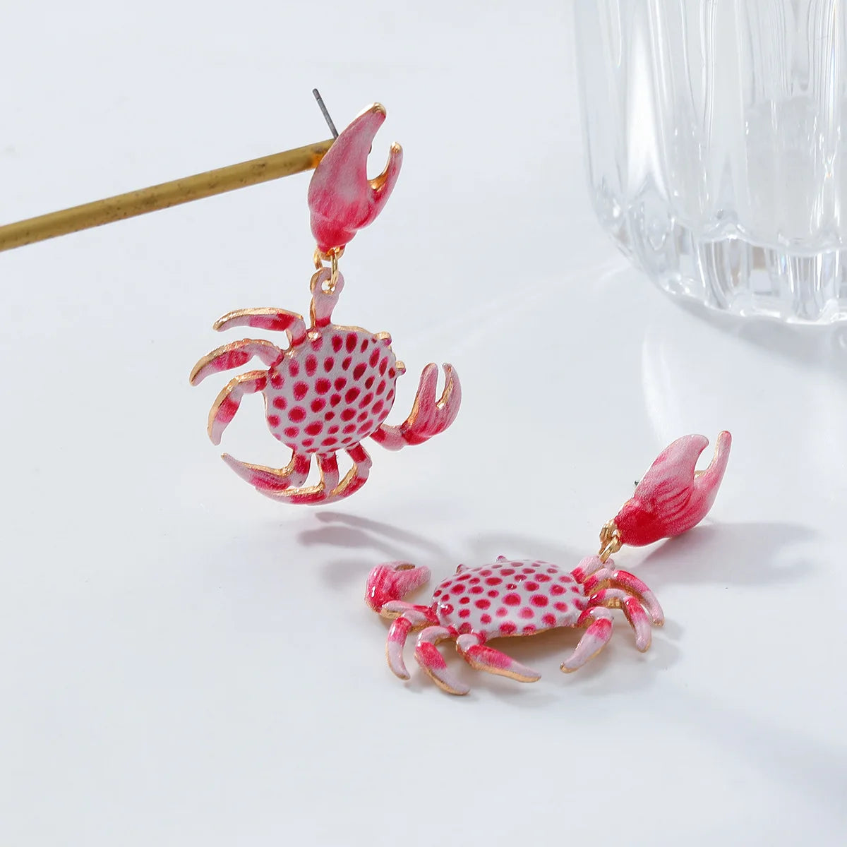Pink crab-shaped earrings on a white background