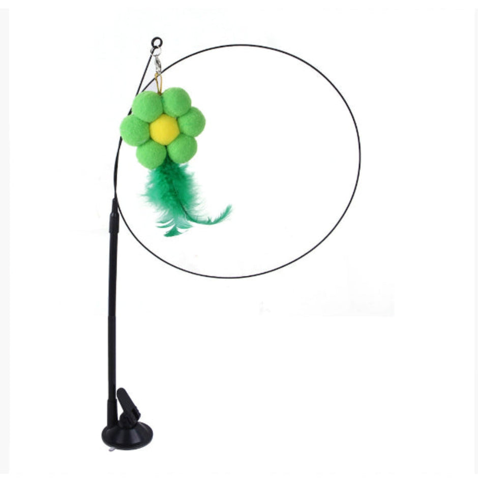 Cat toy with a green flower and yellow center on a black stand against a white background