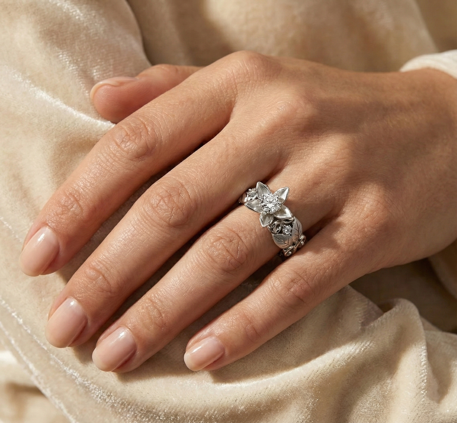 Hand wearing a floral engagement ring, sterling silver on a beige fabric background