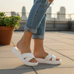 Person wearing white sandals on a rooftop with a cityscape in the background