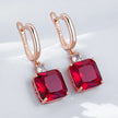 Rose gold earrings with red gemstones on a white background