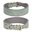 Two green leather dog collars with floral embossing on a white background.