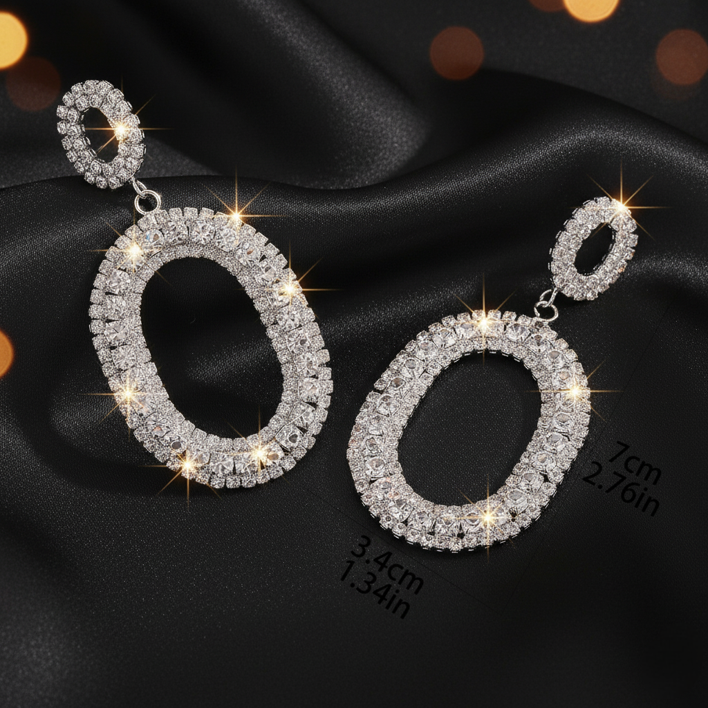 Pair of silver hoop earrings with clear gemstones on a black fabric background.