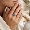 A Hand wearing a symbolic ring for strength with a purple gemstone, blurred background