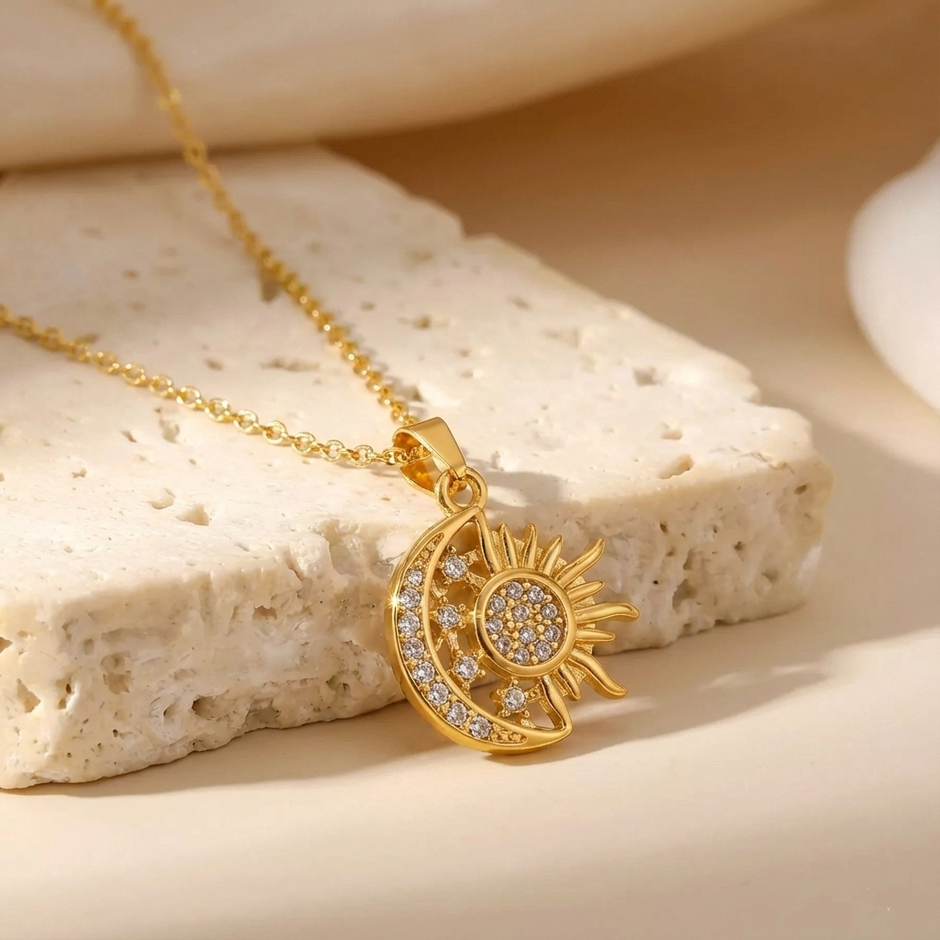 Gold necklace with sun and moon pendant on a textured beige surface