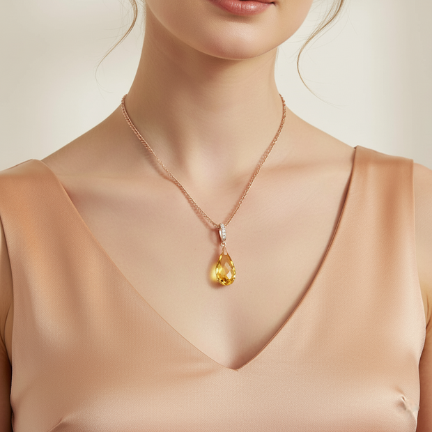 Woman wearing a necklace with a yellow teardrop pendant on a neutral background