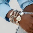 Close-up of a wrist wearing multiple silver bracelets with a neutral background