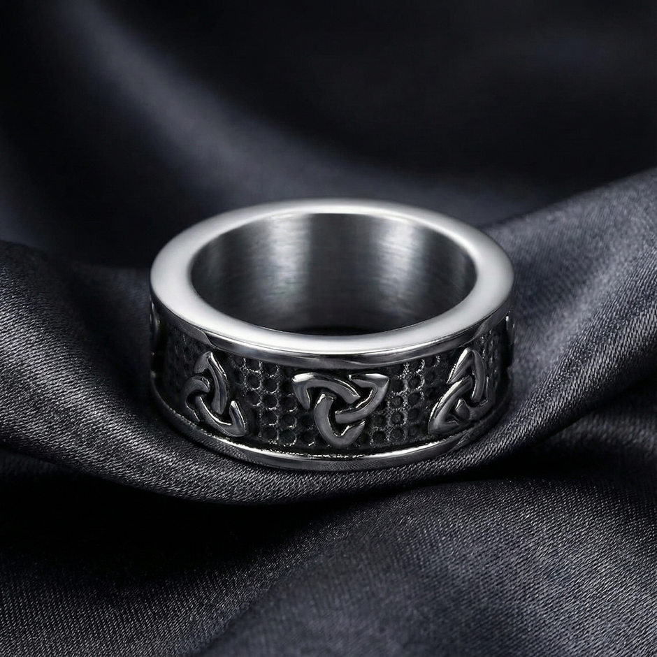 Silver trinity knot ring with intricate design on a dark fabric background