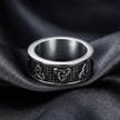 Silver trinity knot ring with intricate design on a dark fabric background