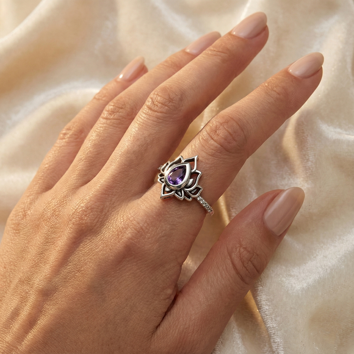 Hand wearing a decorative lotus ring for recovery with a purple gemstone on a soft beige background