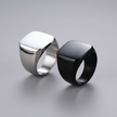 Two rings, one silver and one black, on a gray background