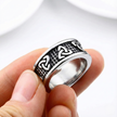 Silver trinity knot ring with intricate design held between fingers on a white background