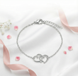 Silver bracelet with heart design on a light background with pink ribbons and flowers